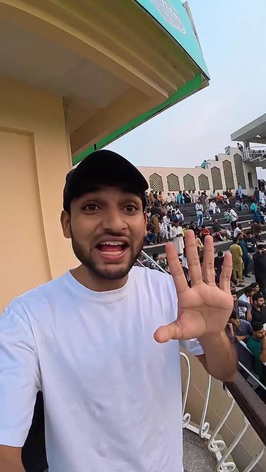 Waleed Ahmad waving to the camera at a cricket stadium