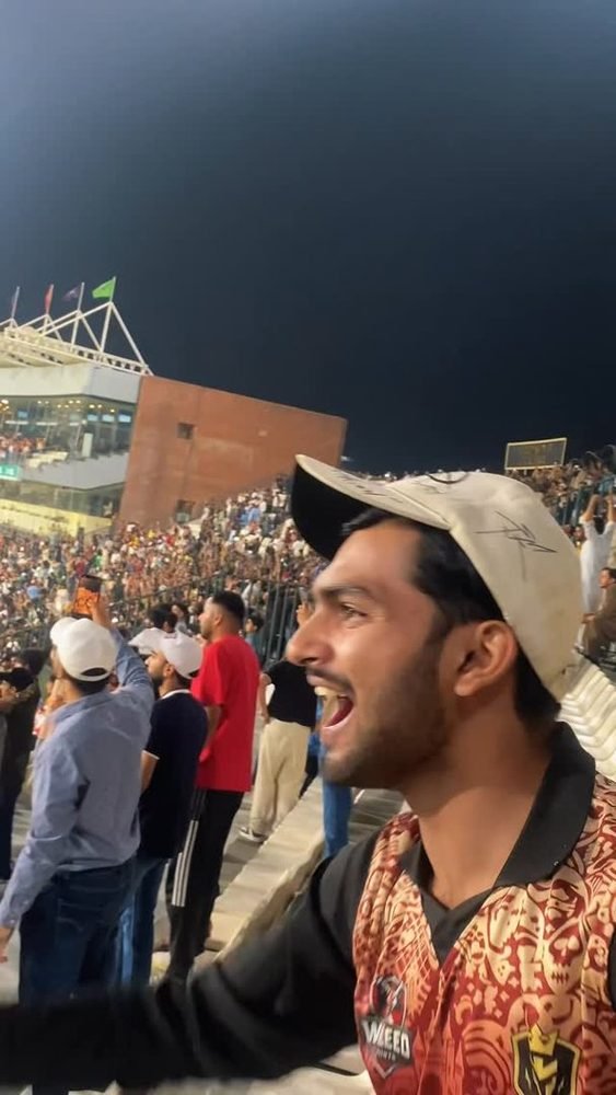 Waleed Ahmad cheering in a stadium crowd at night