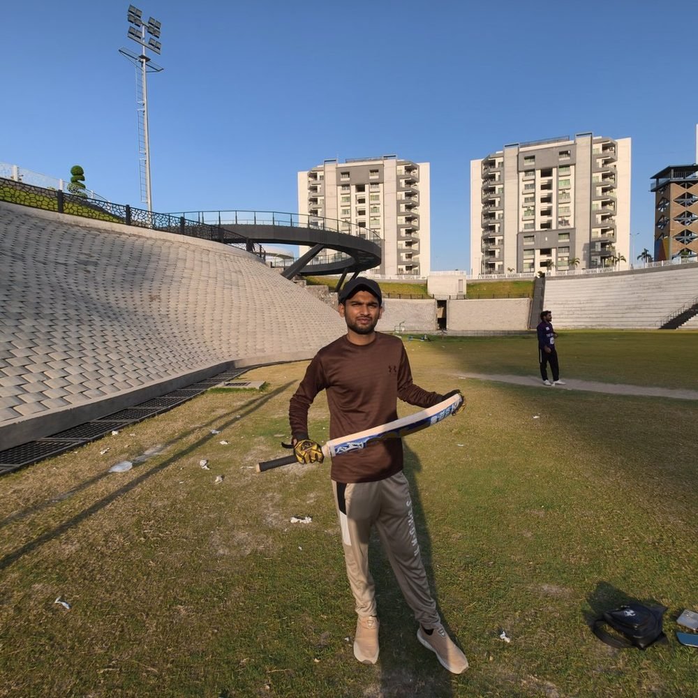Waleed Ahmad holding a cricket bat on a stadium practice pitch